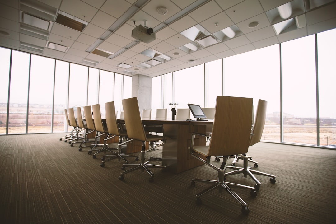 Minimalist boardroom by Bible Verse Daily oval brown wooden conference table and chairs inside conference room