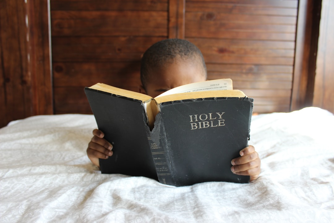 The Inspiring History and Meaning Behind Psalms 📜 by Bible Verse Daily boy reading Holy Bible while lying on bed